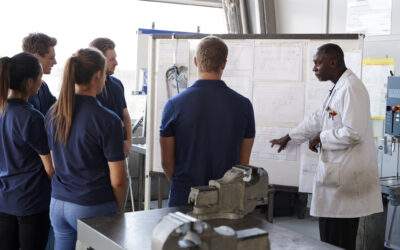 Engineer instructing apprentices at a whiteboard, close up